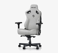 A light gray fabric gaming chair with black armrests, base, and side supports, shown on a white background with a black banner at the bottom reading 'Best Budget Big and Tall Gaming Chair by IGN'.